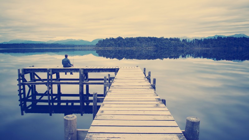 Fisherman sitting on a jetty on a moody winters day